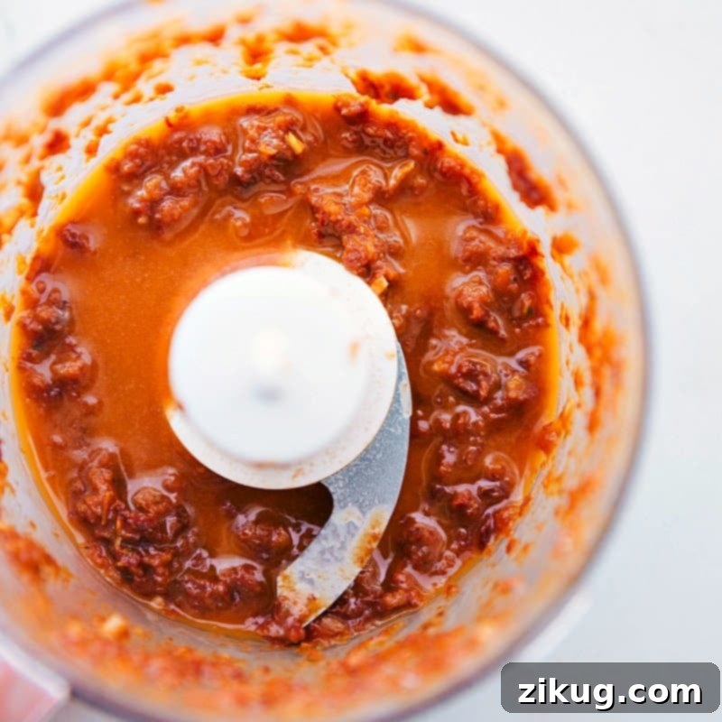 Blending the sun-dried tomato sauce in a food processor, capturing the ingredients coming together to create a flavorful sauce.