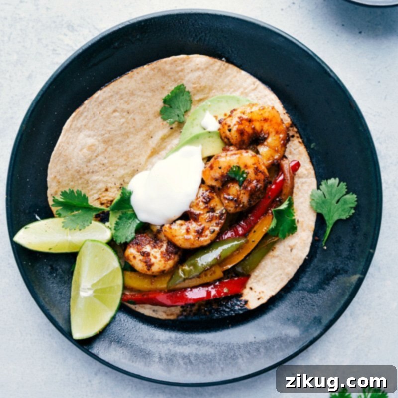 Delectable Shrimp Fajita Wrapped in a Warm Tortilla A tortilla filled with freshly baked seafood and vegetables, garnished with fresh herbs, sour cream, and limes, creating a mouthwatering and visually appealing dish.