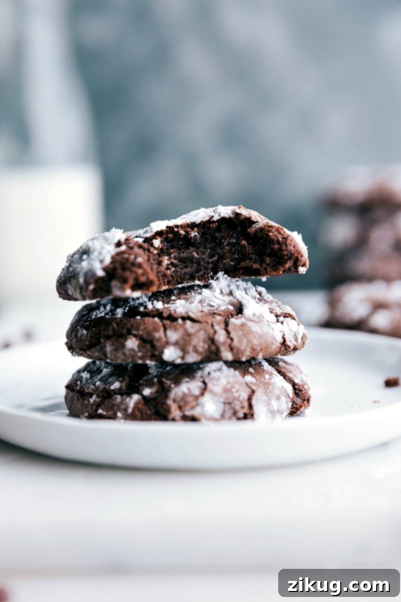 Trio of Chocolate Crinkle Cookies - Showcasing Soft and Gooey Centers and Perfect Cracks The finished chocolate crinkle cookie recipe, with cookies stacked high and one split open to reveal their incredibly soft, gooey, and fudgy interiors. A truly irresistible treat.