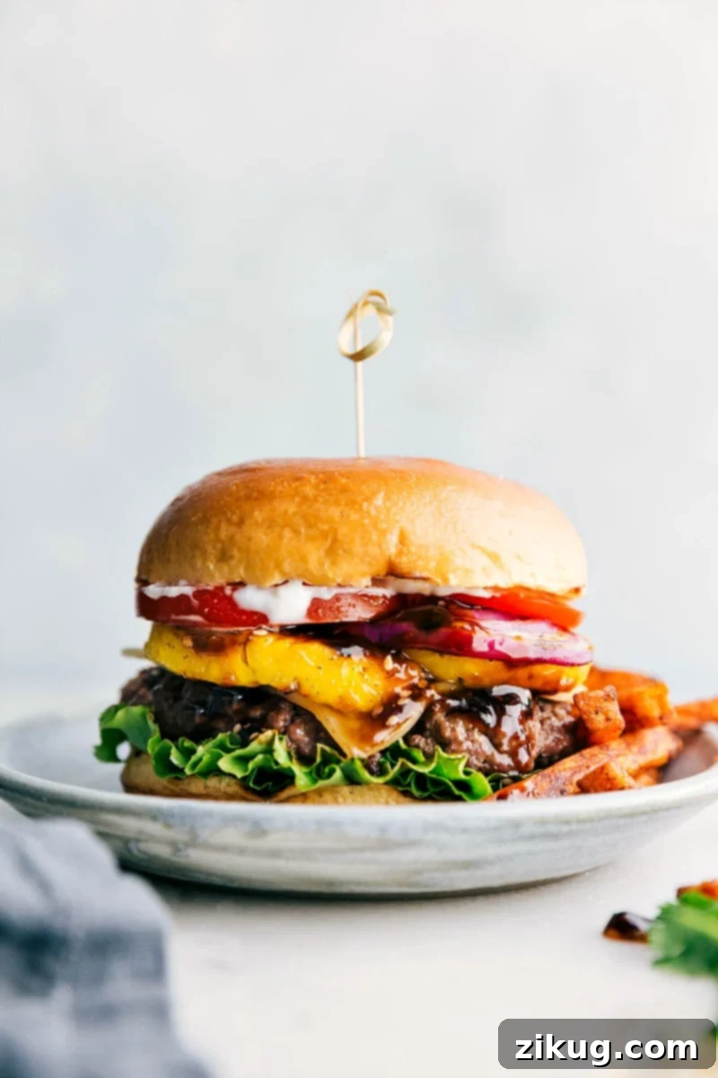 Delicious Teriyaki Burger with Toppings and Fries - Ready to Savor A mouth-watering teriyaki burger, fully assembled with all its toppings nestled between buttery brioche buns, served alongside golden fries.