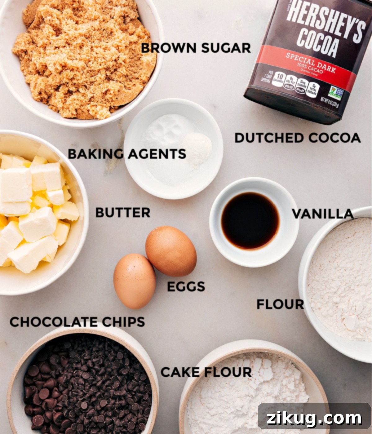 Carefully arranged ingredients for chocolate cookies including cocoa powder, flours, sugars, butter, eggs, and chocolate chips, ready for baking preparation.