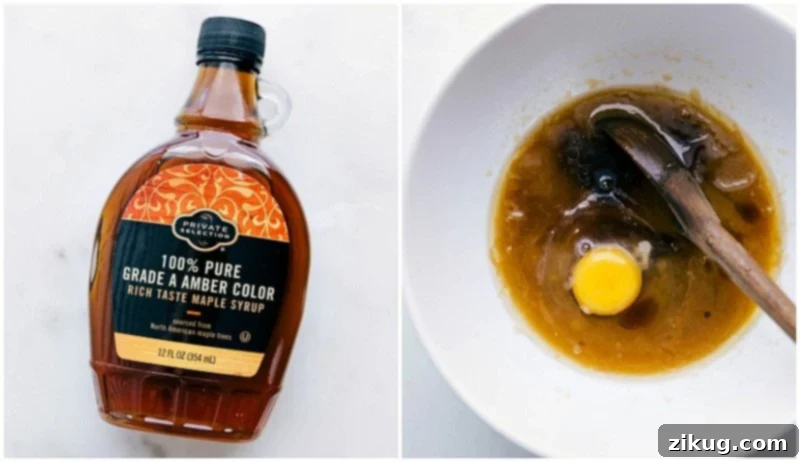A bottle of rich maple syrup and a fresh egg being carefully added to the creamy butter and sugar mixture in a mixing bowl, enriching the M&M cookie batter.