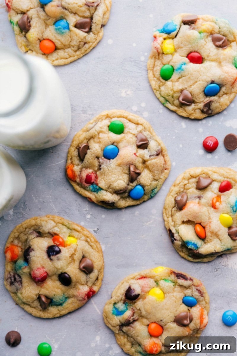 A beautiful arrangement of freshly baked M&M cookies alongside a refreshing glass of milk, perfect for a delightful snack or dessert. The cookies showcase vibrant colors and a tempting texture.