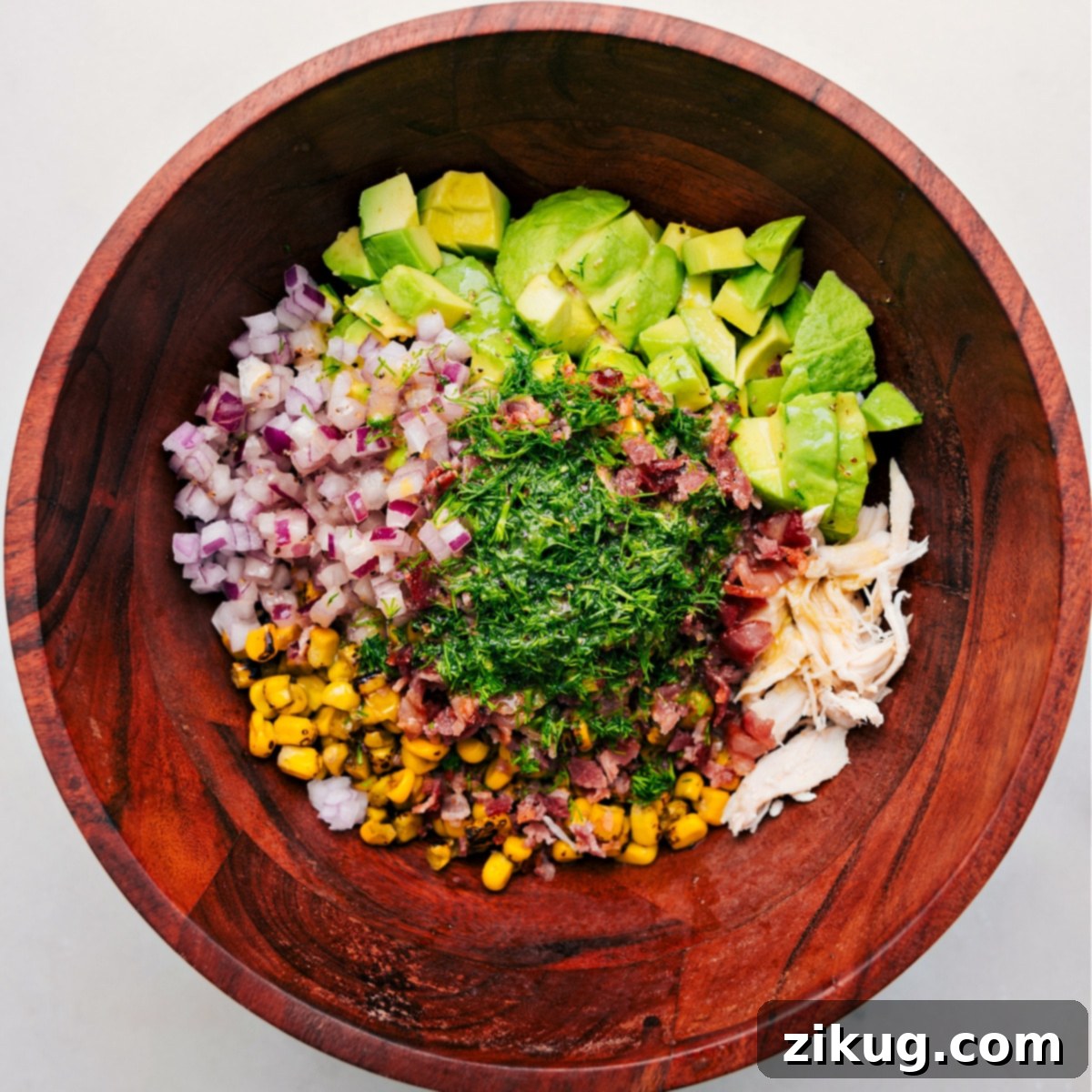 How To Make Chicken Avocado Salad A large bowl containing all the fresh ingredients of the Avocado Chicken Salad, before being tossed with the dressing.