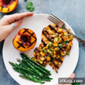 Zesty Peach Salsa Chicken 2 Peach salsa chicken served on a plate, accompanied by green beans and a freshly grilled peach on the side.