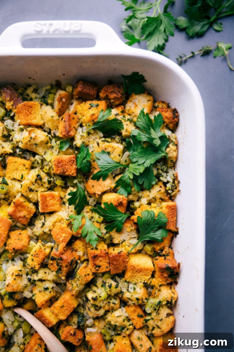 A golden-brown, hearty cornbread dressing, fresh from the oven, garnished with fresh herbs, and ready to be enjoyed as the ultimate comfort food.