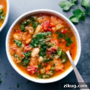 A delicious bowl of White Bean and Kale Soup, garnished with fresh herbs and Parmesan.