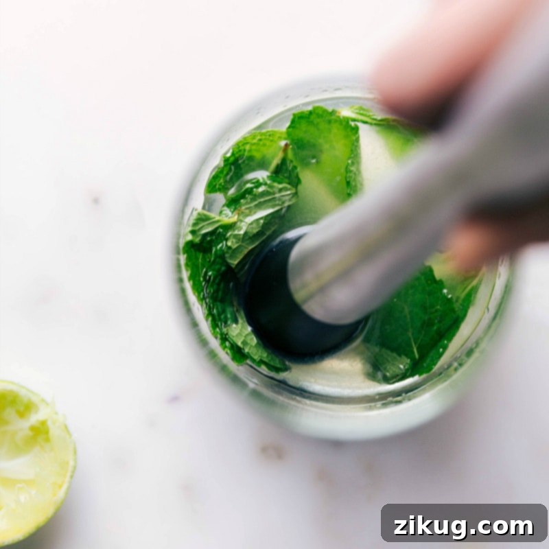 Refreshing Virgin Mojito 3 Mint leaves being muddled in a glass, releasing their aroma and flavor for the refreshing drink.