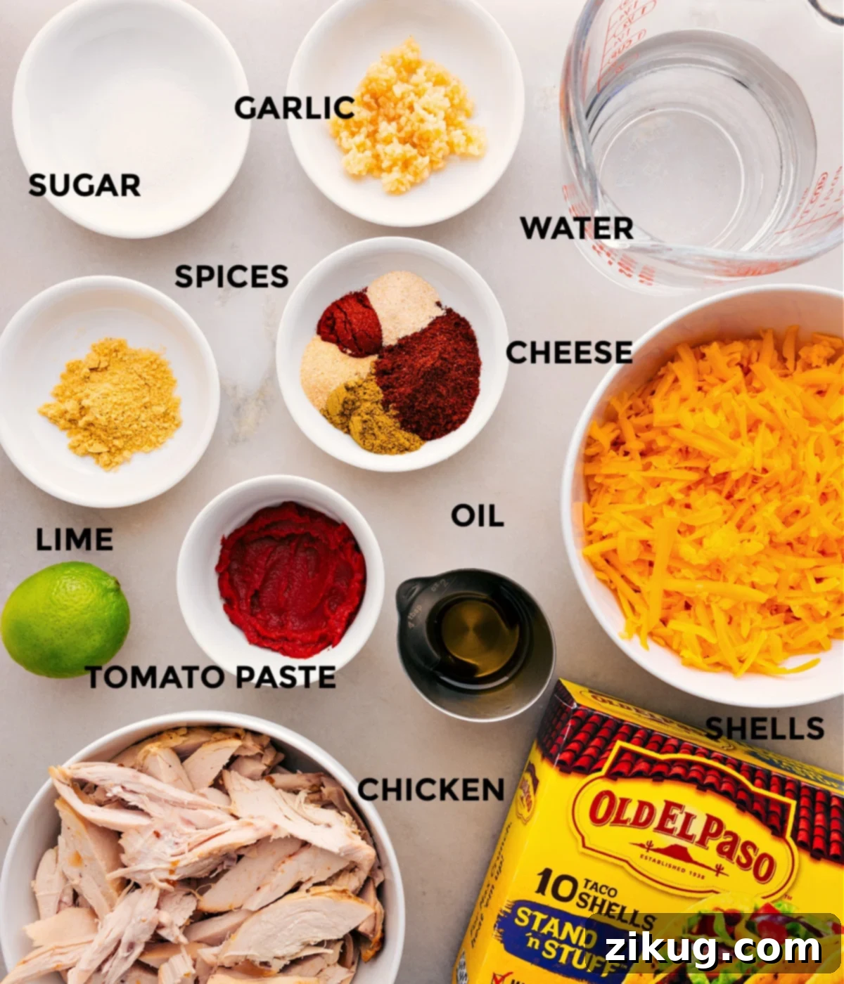 Ingredients In Rotisserie Chicken Tacos Essential ingredients for Rotisserie Chicken Tacos laid out: shredded chicken, spices, tomato paste, lime, garlic, sugar, cheese, shells, and water.