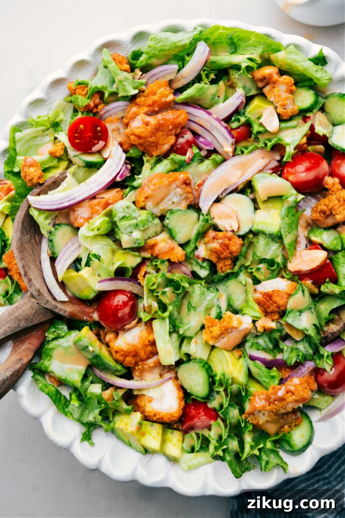 A large bowl of Crispy Chicken Salad drizzled generously with homemade honey BBQ dressing, ready to be enjoyed.