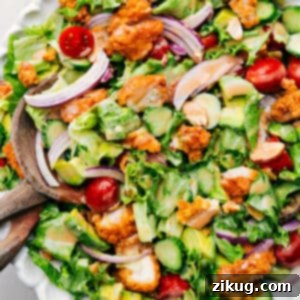 A beautifully plated Crispy Chicken Salad with dressing and a side of fresh ingredients.