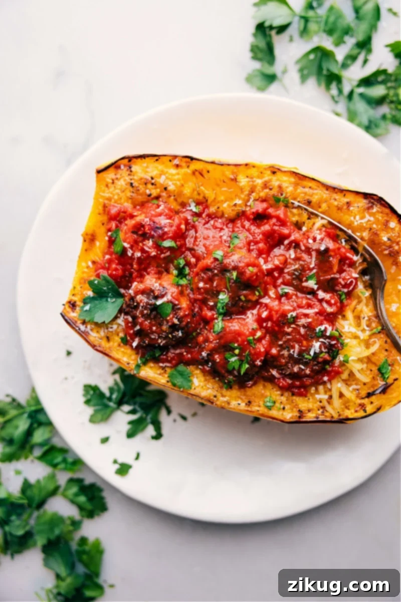Finished spaghetti squash filled with rich marinara sauce and tender meatballs, garnished with fresh cheese and vibrant herbs.