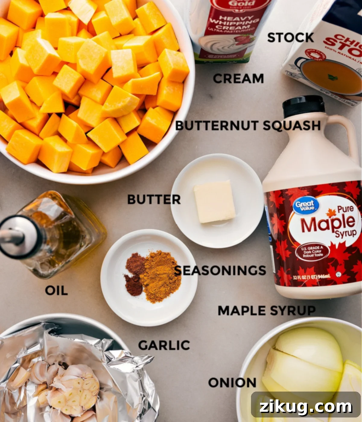 A vibrant selection of fresh ingredients laid out for the butternut squash soup: cubed butternut squash, yellow onion, garlic, olive oil, butter, an array of spices, chicken stock, maple syrup, heavy cream, and pepitas.