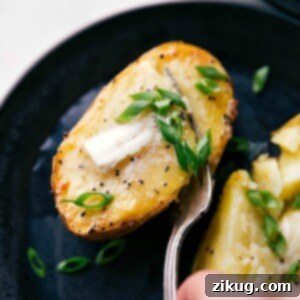 Freshly baked potatoes topped with melting butter and sprinkled with vibrant green chives, ready to be eaten.