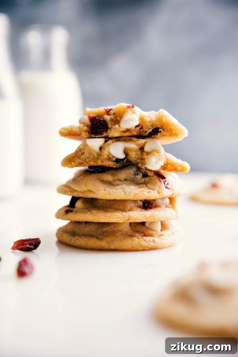 White Chocolate Cranberry Cookie Bliss: A Warm, Gooey Interior Unveiled Stack of white chocolate cranberry cookies split open, revealing a gooey, warm interior with melted white chocolate and cranberries. Perfect for holiday gatherings.