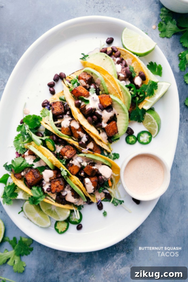 Overhead image of perfectly assembled Butternut Squash Tacos with creamy sauce and fresh toppings on a rustic tray, ready to be enjoyed.