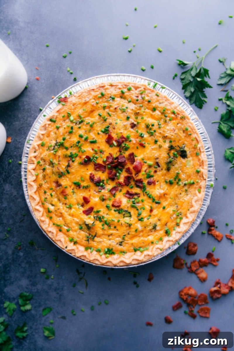 This Broccoli Cheddar Quiche is loaded with tender broccoli, sharp Cheddar cheese, and a creamy egg custard. The perfect breakfast, lunch, or dinner! Recipe via ChelseasMessyApron. A perfectly baked and sliced Broccoli Cheddar Quiche, garnished with fresh chives and reserved crispy bacon, ready to be served and enjoyed.