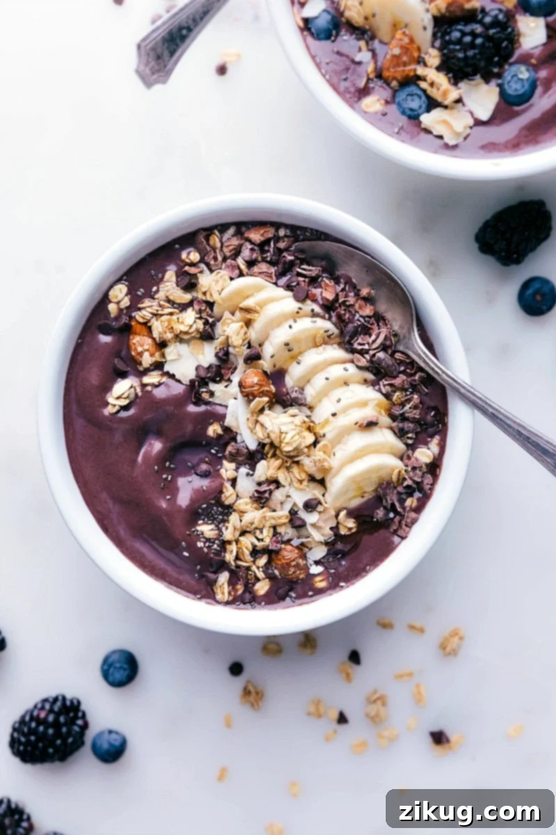 Delicious Açaí Bowl with Almond Butter and Assorted Toppings A beautifully presented Chocolate Almond Butter Açaí bowl, topped with a colorful assortment of fresh berries, crisp granola, sliced banana, and a generous drizzle of nut butter, with a spoon nestled alongside.