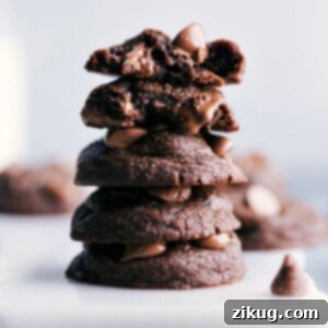 Stacked fudge brownie cookies with one split in half to reveal their rich and gooey inside.