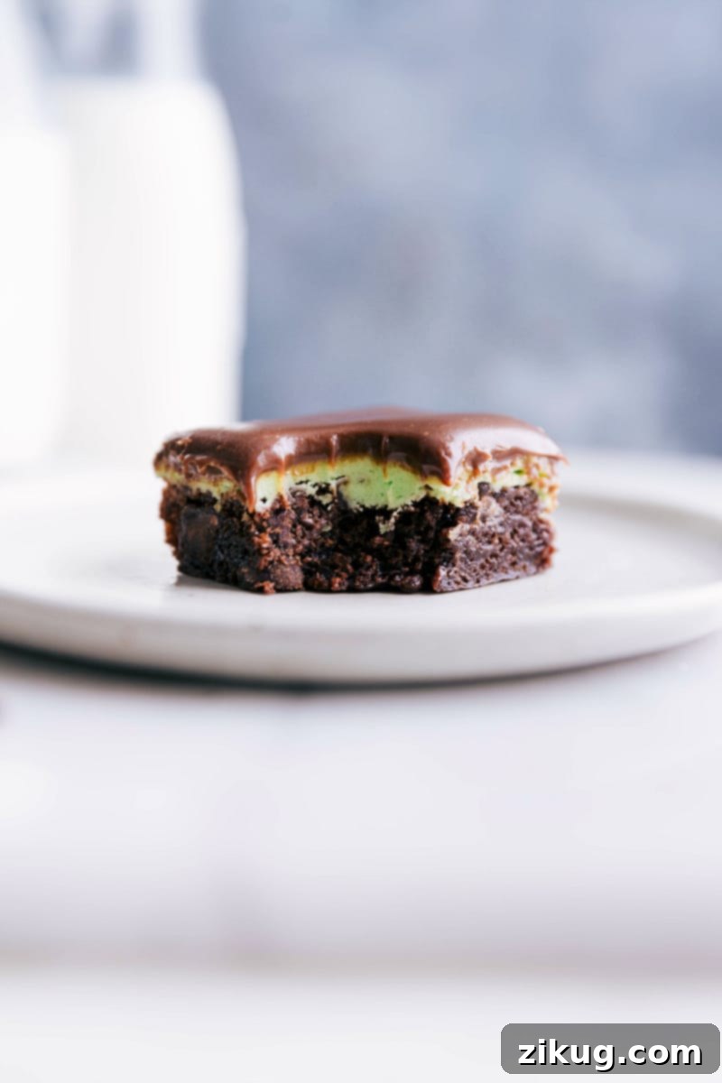 Chocolate mint brownies on a plate with a bite taken out of it, revealing its delicious interior.