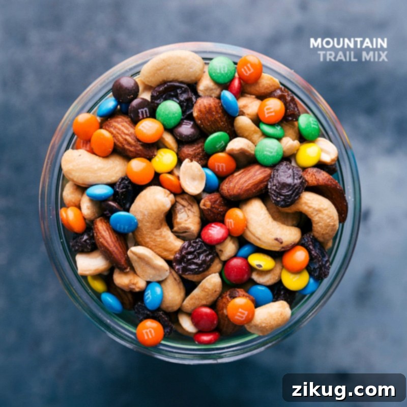A clear glass jar filled with the finished mountain snack, showcasing an array of complementing flavors from various ingredients like nuts, chocolate, and dried fruit.