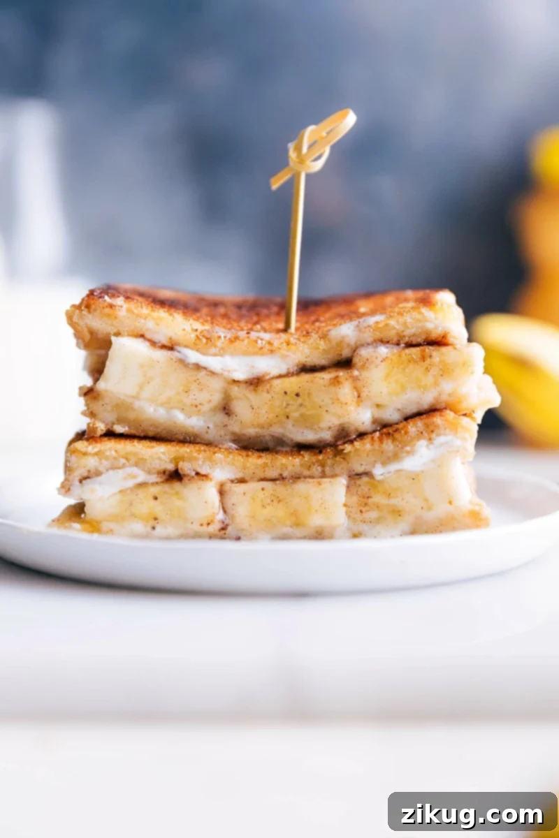 This Honey and Banana Grilled Cheese Sandwich is a delectable treat, perfect as breakfast, brunch, or dessert. It features rich buttered brioche bread, creamy mascarpone cheese, thick banana slices, sweet honey, and aromatic cinnamon, all grilled until golden and caramelized. A truly quick, easy, and satisfying sweet sandwich recipe. Grilled Honey and Banana Sandwiches stacked on top of each other, showcasing caramelized brioche and creamy filling