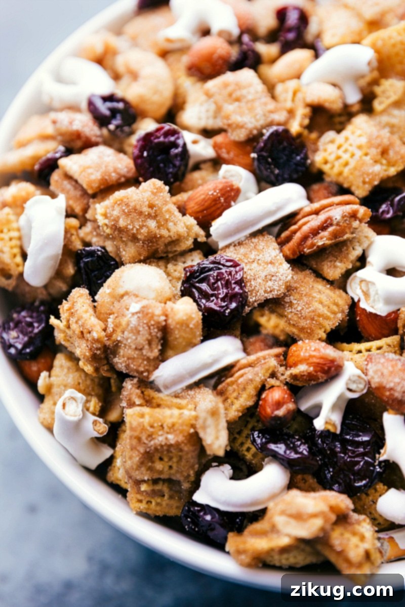 Overhead shot of the finished Dried Cherry Snack Mix in a beautiful serving bowl, ready to be enjoyed. Features cereal, nuts, dried cherries, and yogurt pretzels.