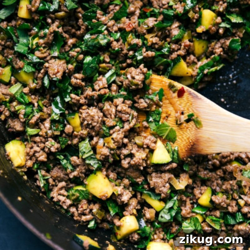Serving Delicious and Freshly Cooked Larb Beef from the Pan Wooden spoon serving a portion of the finished Larb Beef dish from a hot pan, ready to be plated.