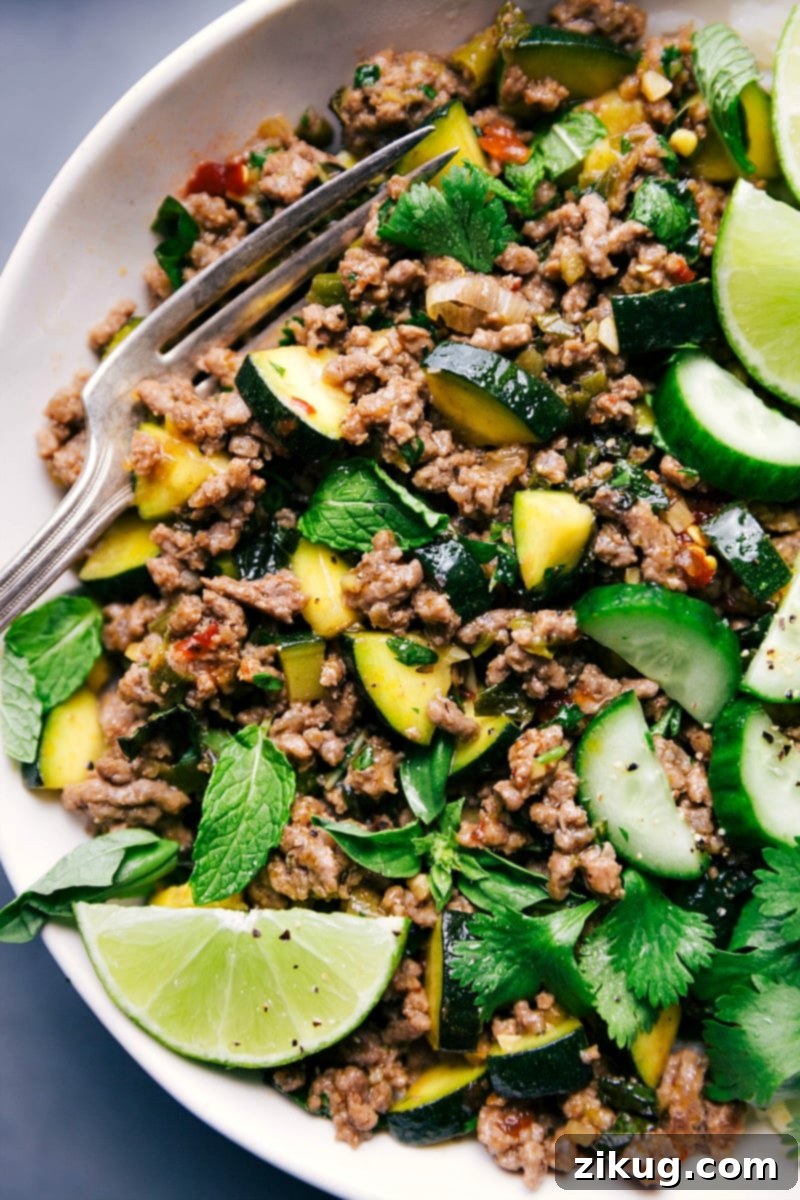 Ready-to-Eat Beef Larb with Fresh Lime and Herb Garnishes A plate of finished Beef Larb, garnished with fresh lime wedges and a sprig of mint, ready to be savored.