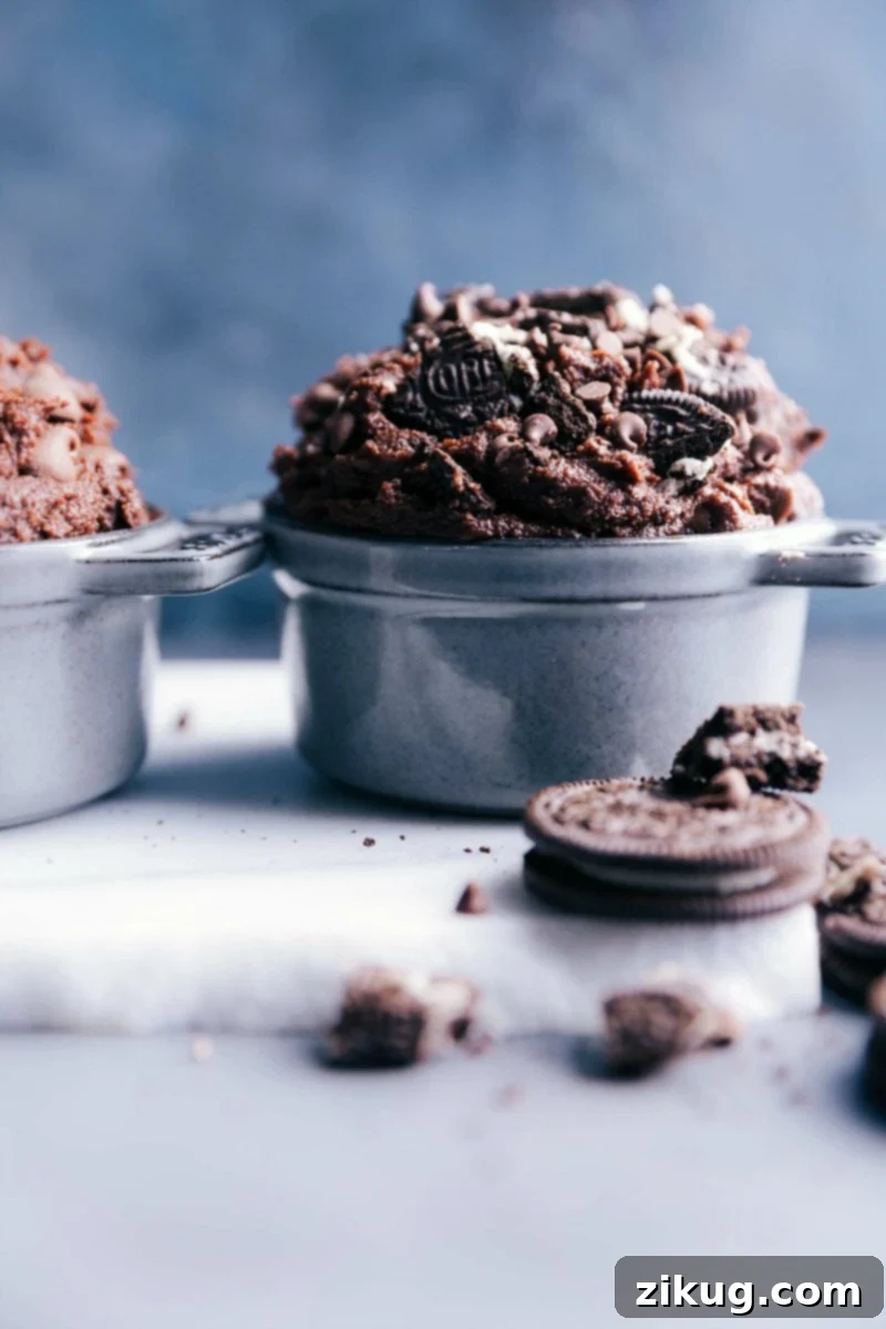 Edible brownie batter in a bowl, enhanced with chunks of Oreos and chocolate chips, ready to be enjoyed.