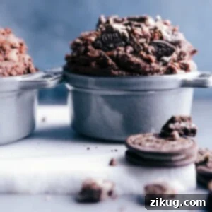 Edible brownie batter in a bowl, enhanced with chunks of Oreos and chocolate chips.