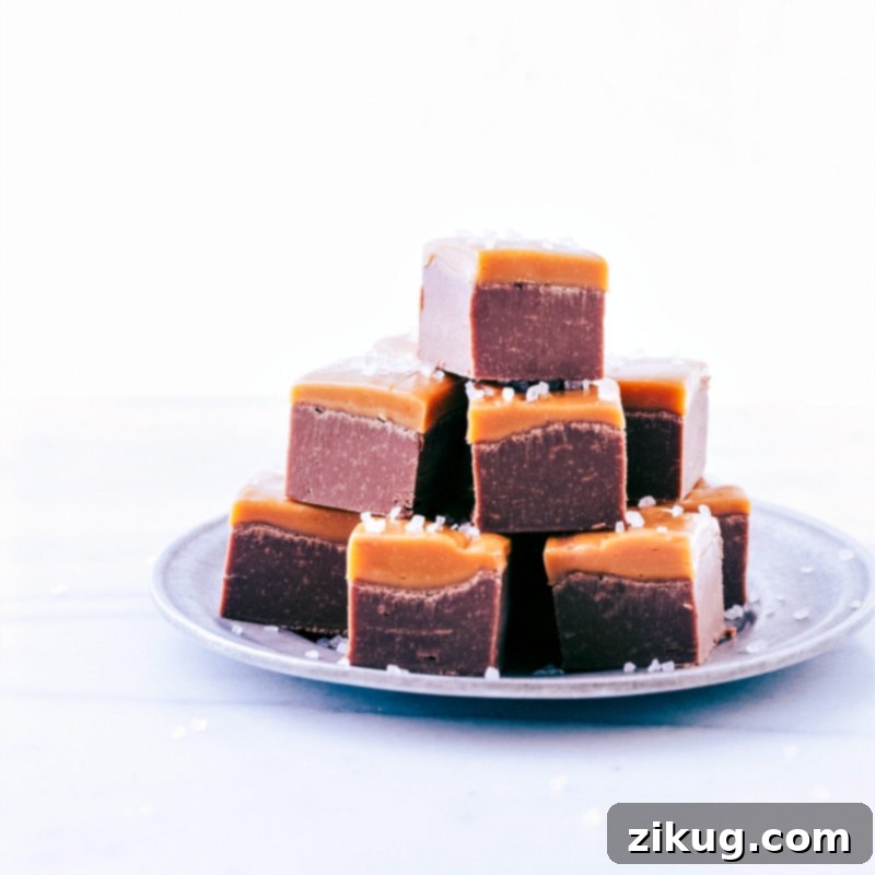 Favorite Microwave Fudge Squares Perfectly cut Microwave Fudge cubes, stacked invitingly on a white plate, showcasing the smooth texture and caramel layer.