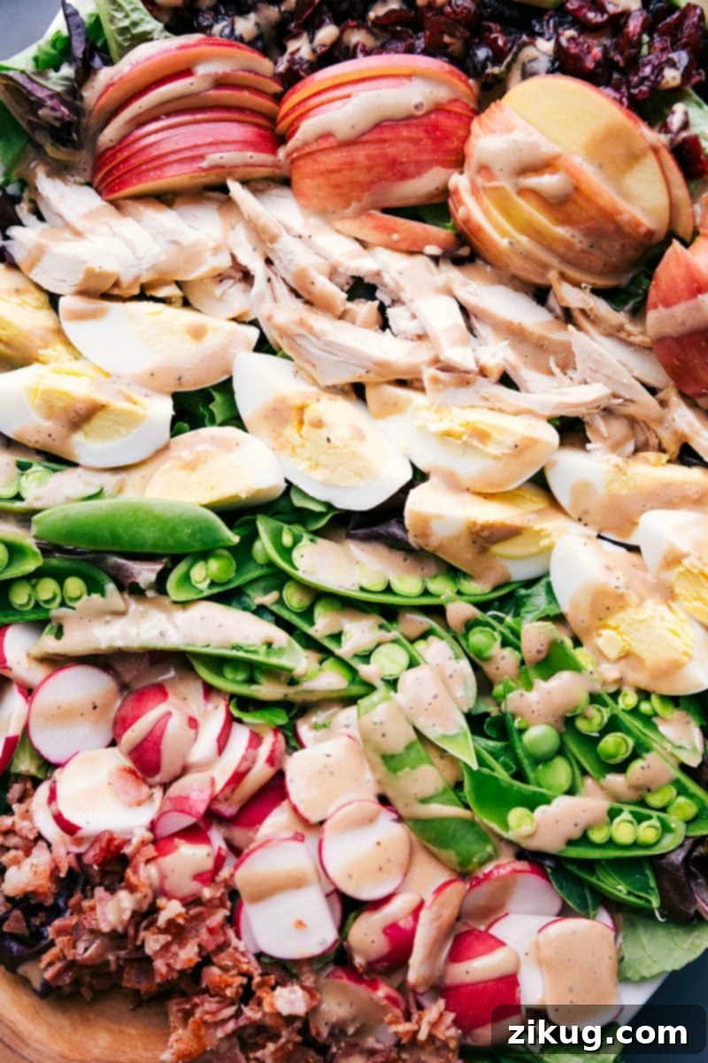 Vibrant Finished Salad with Apples, Chicken, Eggs, Peas, and Radishes Completed salad, artfully arranged to highlight apples, chicken, hard-boiled eggs, sugar snap peas, and radishes.