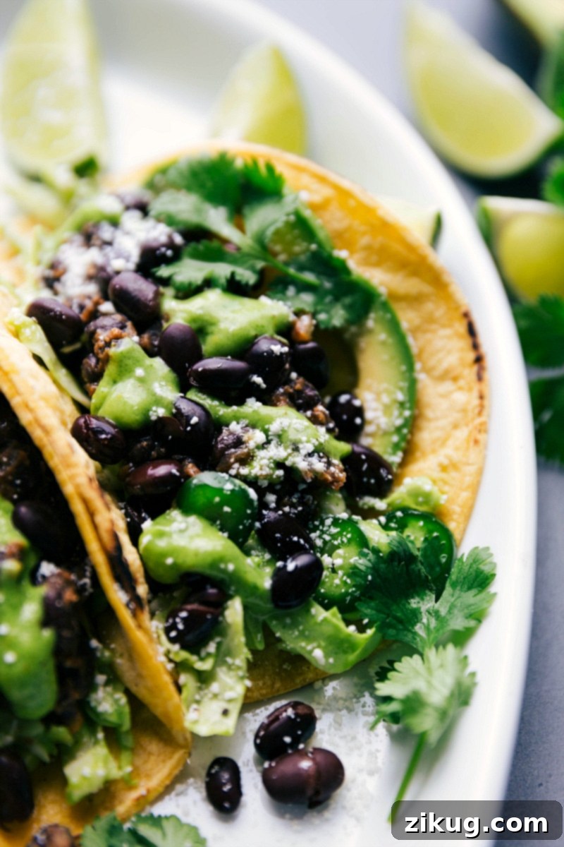 Savory Black Bean Tacos Topped with Homemade Sauce, Cheese, and Cilantro, Ready for Enjoyment. Delicious and savory Black Bean Tacos generously topped with homemade cilantro sauce, crumbled Cotija cheese, and fresh cilantro, perfectly arranged and ready to be savored.
