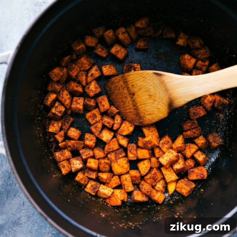 Flavorful Sweet Potato Sauté: A Foundation for Hearty Chili Sweet potatoes being expertly sautéed with a blend of aromatic seasonings in a pan, deepening their flavor for the Quinoa Chili.