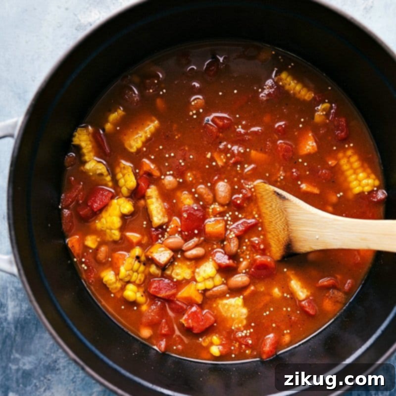 Integrating Vegetables and Beans: Completing the Quinoa Chili Base A colorful medley of vegetables and beans being gently stirred into a pot, creating a harmonious blend of flavors and textures for the Quinoa Chili.
