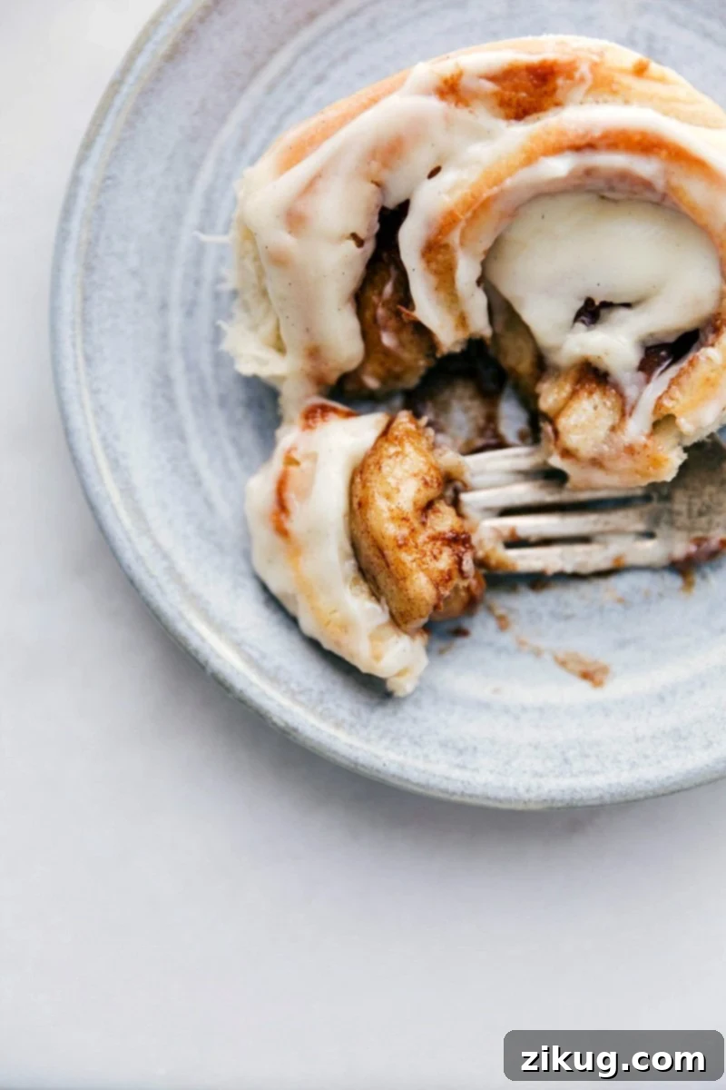 Deliciously gooey Homemade Cinnamon Rolls with step-by-step guide and expert tips. Up-close photo of a Homemade Cinnamon Roll with a bite taken out of it, showcasing its gooey center and luscious frosting.