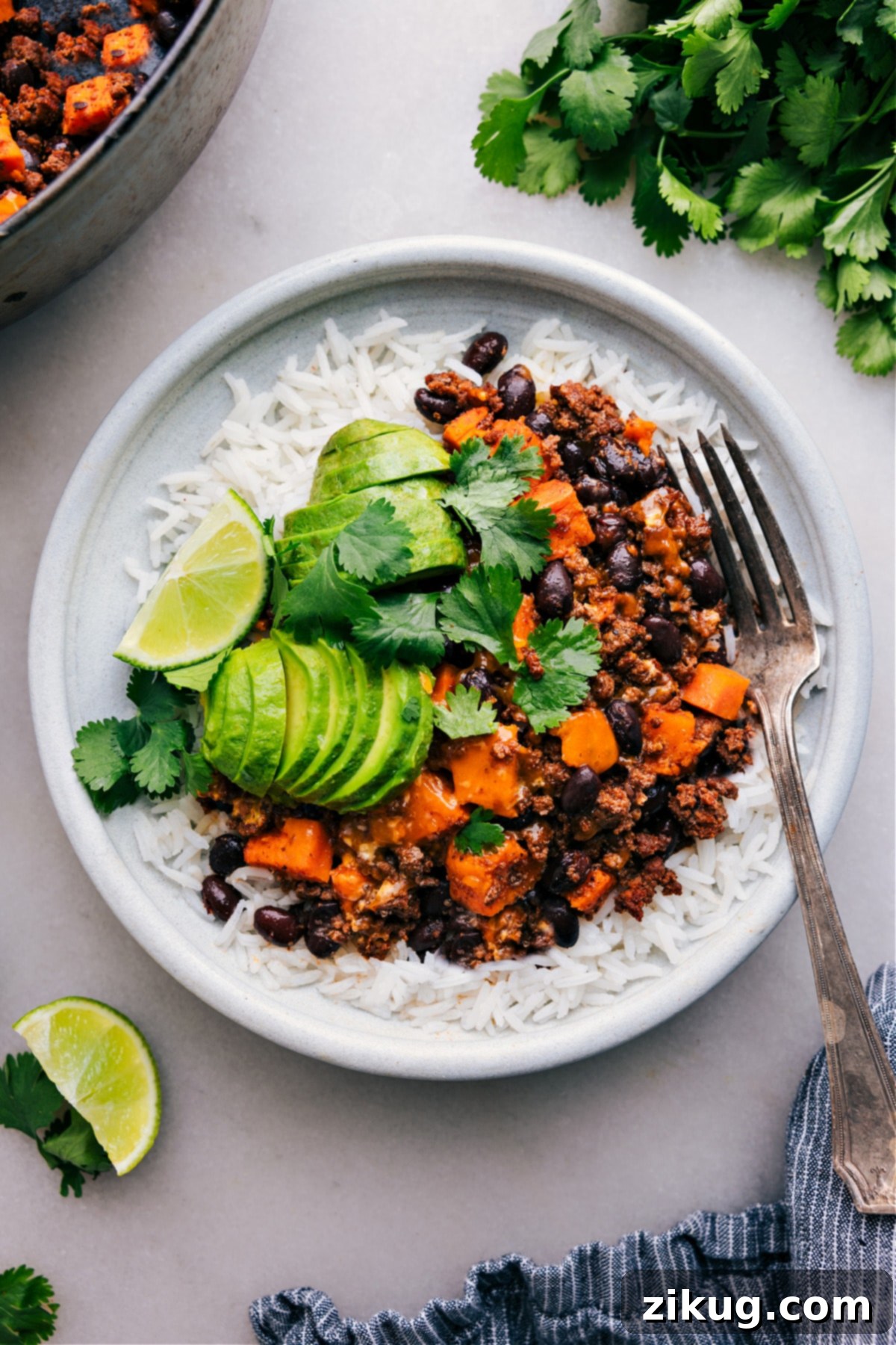 Ground Turkey Sweet Potato All Made In One Skillet Ground Turkey Sweet Potato Skillet served on a plate of rice with fresh avocado, cilantro, and lime on the side, highlighting it as a complete and satisfying meal.