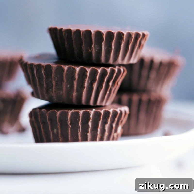 Healthy Cookie Dough Cups: A delightful and wholesome treat for any occasion Close-up view of three Healthy Cookie Dough Cups stacked on a plate, highlighting their perfectly set chocolate and smooth texture.