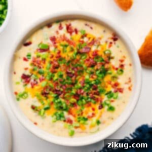 A beautiful top-down shot of a large bowl of Loaded Potato Soup, rich and creamy, generously topped with crispy bacon, melted cheddar cheese, and fresh green onions, inviting you to enjoy this ultimate comfort food.