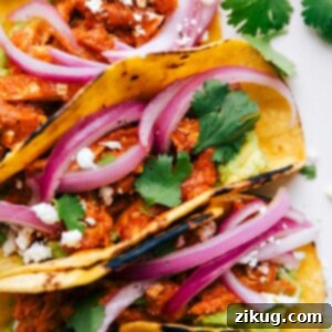 Smoky Chicken Tinga Tacos 4 A fully assembled and stuffed meal, filled with pickled red onions, guacamole, and cilantro.