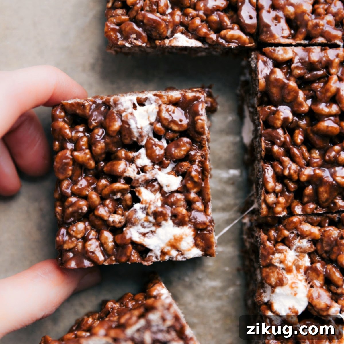 The Best Gooey Chocolate Rice Krispie Treat Recipe A gooey chocolate Rice Krispie treat being pulled apart, showcasing its soft, marshmallowy texture.