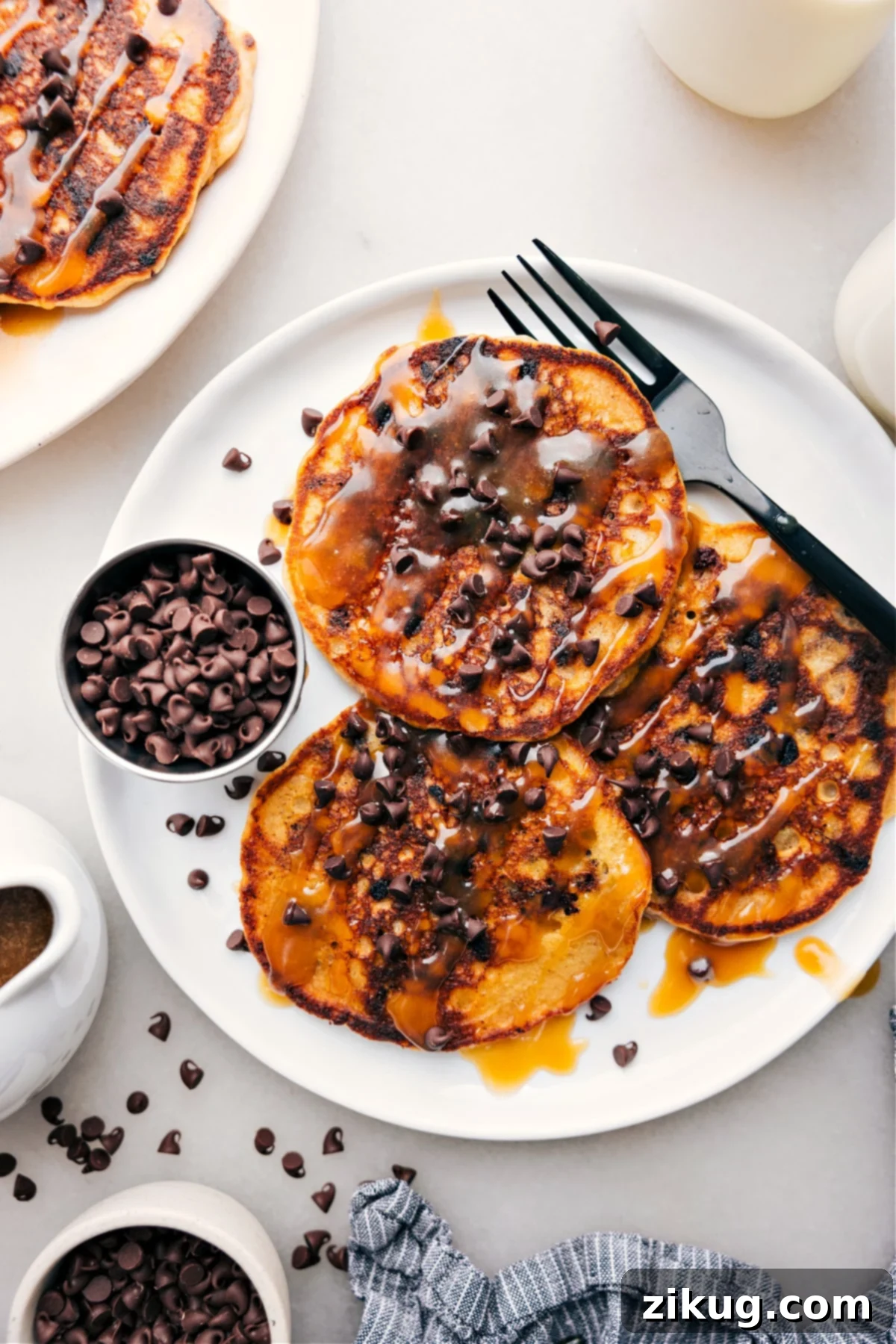 Stack of fluffy chocolate chip pancakes drizzled with syrup.