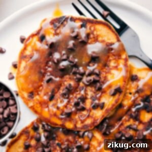 Perfectly stacked chocolate chip pancakes with syrup.