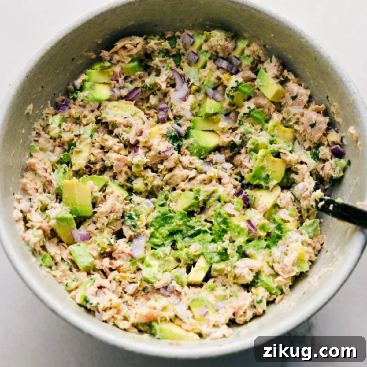 Quick and Simple Avocado Tuna Salad Ready for Serving A large, inviting bowl of creamy Avocado Tuna Salad, perfectly mixed with visible chunks of avocado, flaked tuna, and crisp vegetables. It's ready to be served on toasted bread as a delightful sandwich or enjoyed in any preferred way, highlighting its quick and simple preparation.
