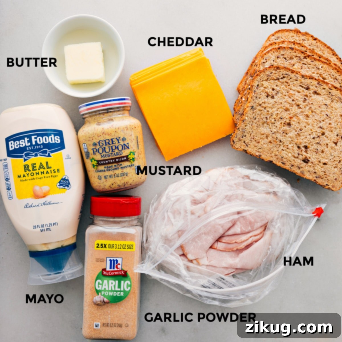 All the ingredients for a delicious ham and cheese sandwich, including whole grain bread, cheddar cheese, deli ham, butter, mayonnaise, country mustard, salt, and garlic powder, prepped out for easy assembly.