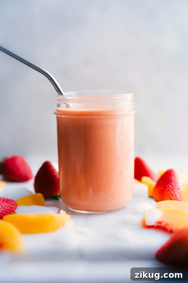 Delicious Peach Smoothie with frozen peaches, strawberries, mango, banana, and orange juice. A vibrant and creamy peach smoothie garnished with fresh fruit, ready to be enjoyed.