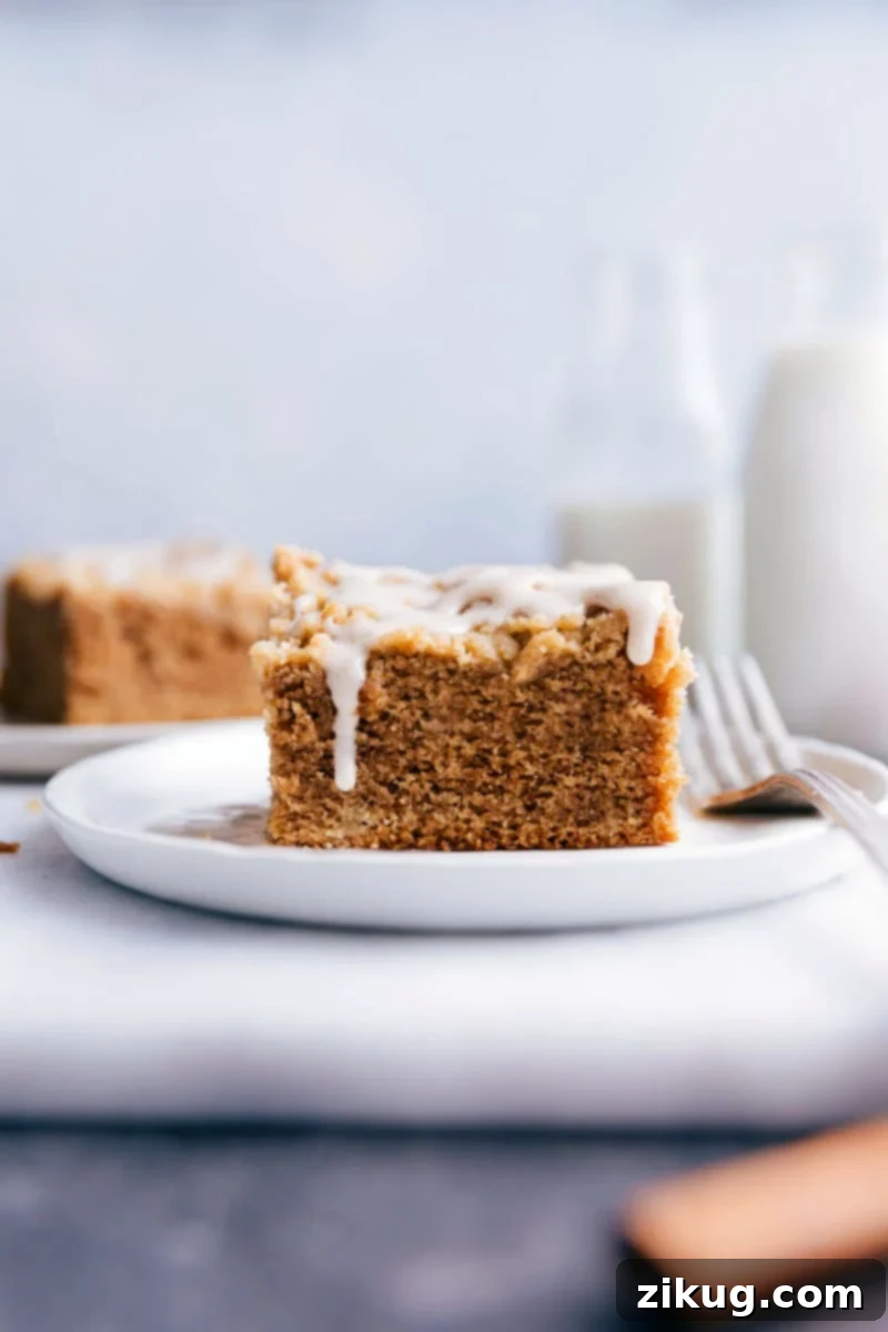 Irresistible Apple Coffee Cake Slice with Glaze - A Fall Delicacy A perfectly sliced piece of Apple Coffee Cake, revealing its moist interior and generous streusel topping, elegantly drizzled with a sweet glaze, ready to be enjoyed.