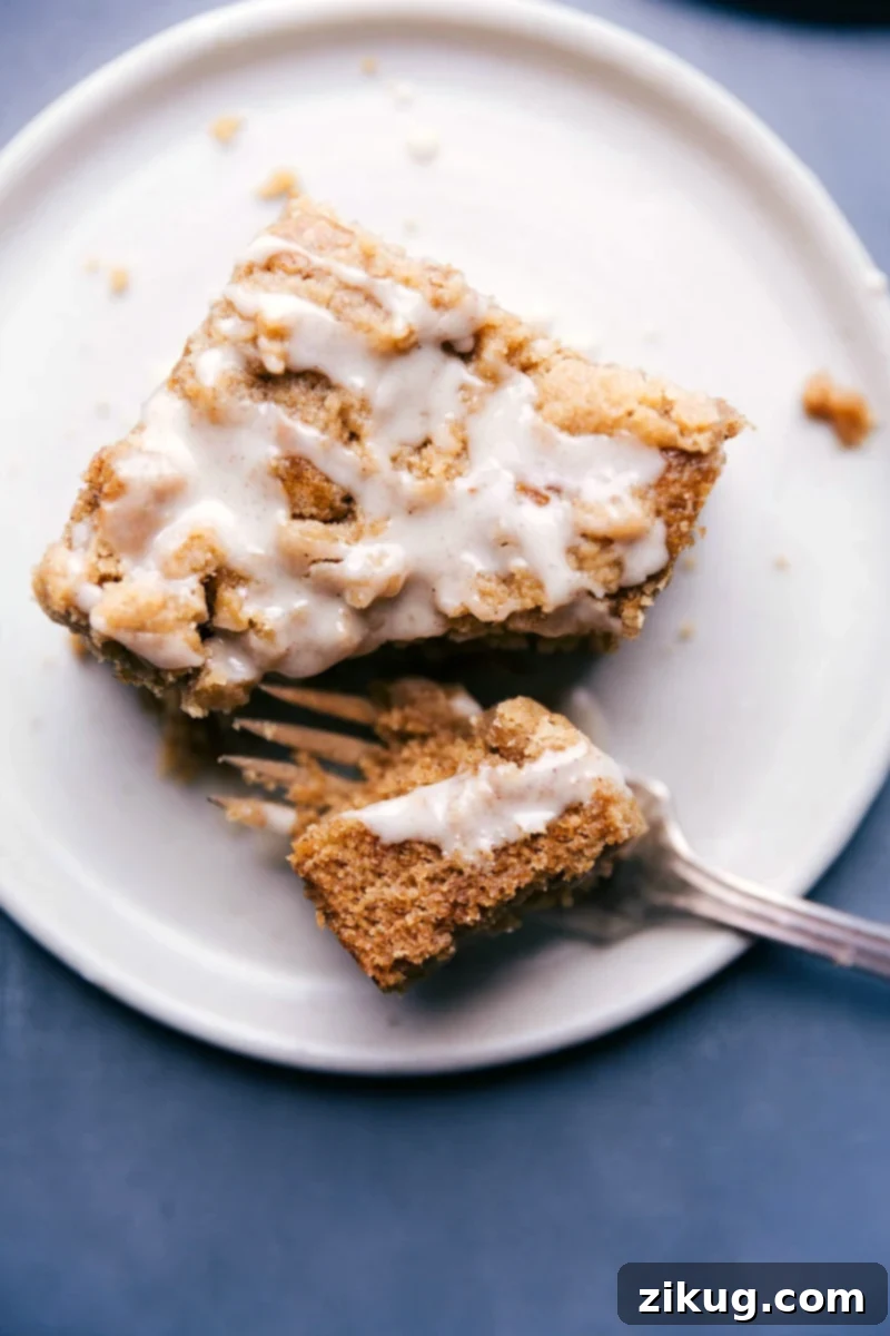 Delicious Apple Coffee Cake Slice, Glazed and Ready to Serve A close-up shot of a single slice of Apple Coffee Cake, exquisitely plated, showcasing its golden-brown streusel, moist cake, and delicate drizzle of apple cider glaze, ready for an indulgent moment.