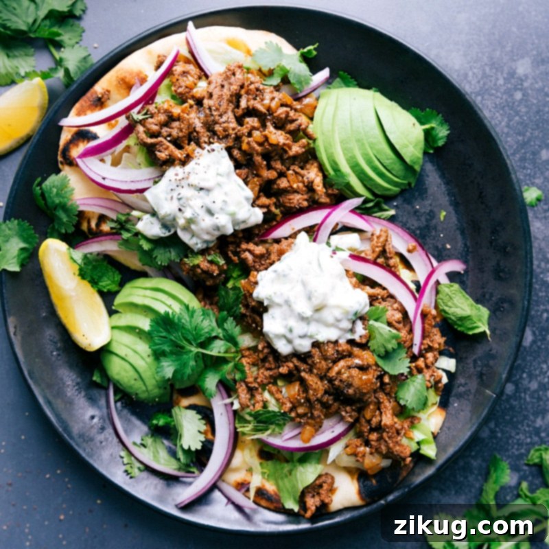 Ground Beef Naan Tacos - A Flavorful and Satisfying Feast A beautifully arranged plate of Ground Beef Naan Tacos, adorned with fresh vegetables, a generous drizzle of herb sauce, and a sprinkle of cilantro, ready to be enjoyed as a flavorful feast.